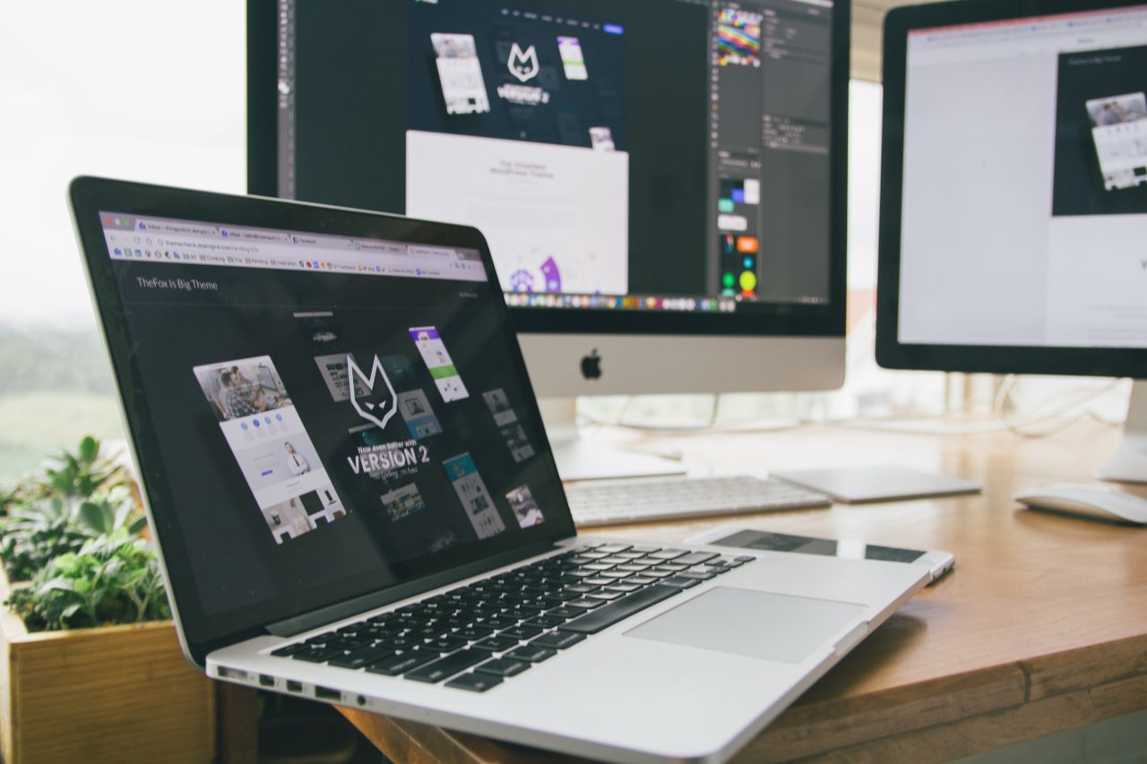 A sleek workspace with a laptop and monitors open to design software.
